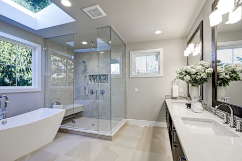 Un bagno spazioso nei toni del grigio con vasca da bagno freestanding ed elegante doccia con box in vetro, che creano un design lussuoso e contemporaneo.